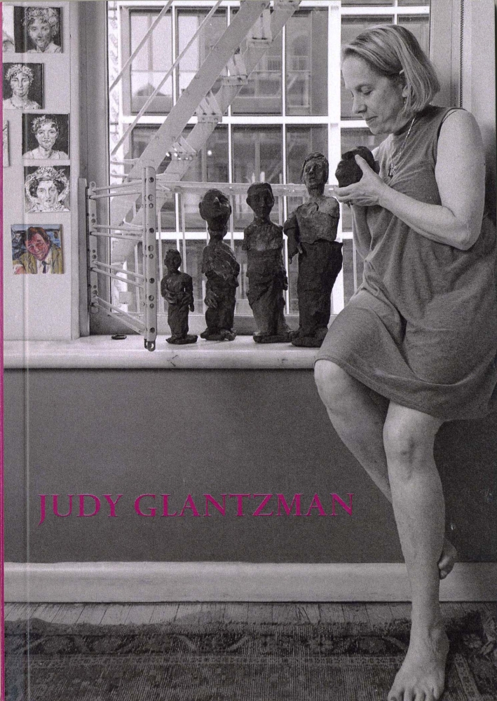 Black and white image of the artist sitting in a windowsill surround by her work. Judy Glantzman is written across the front.