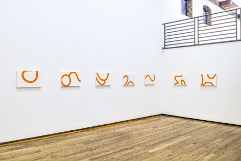 seven white and orange canvases installed on a white wall